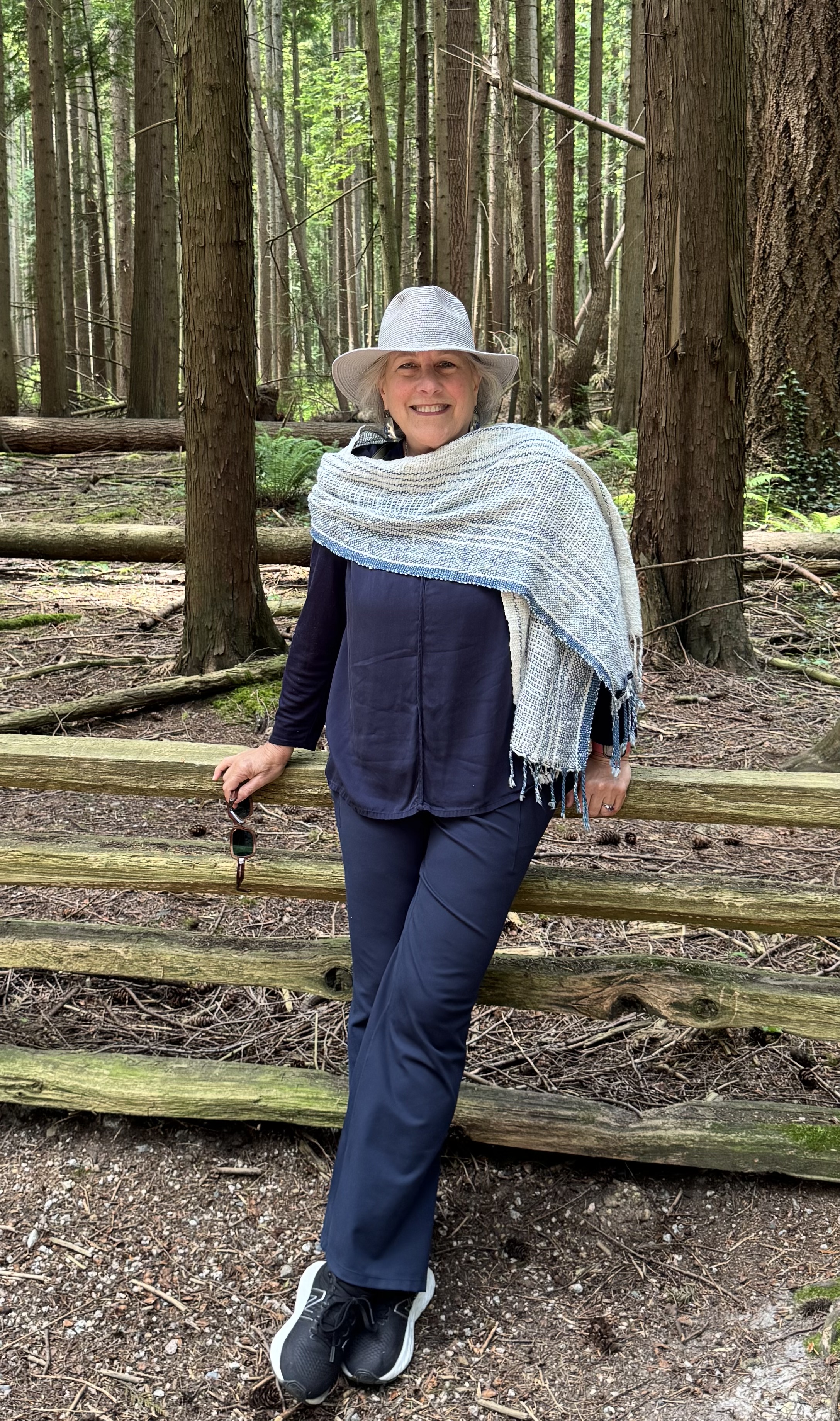 Illana Berger standing among cedars in a woven shawl